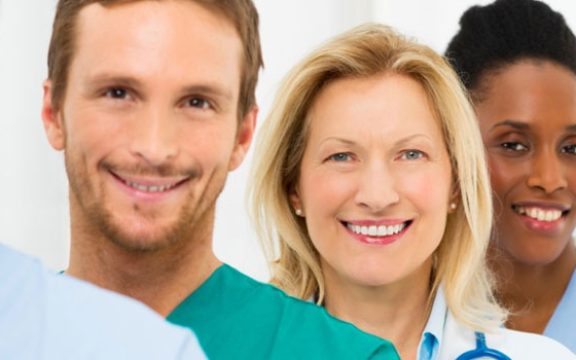 Healthcare professionals smiling together, representing teamwork and career opportunities through a diploma in Health and Social Care.