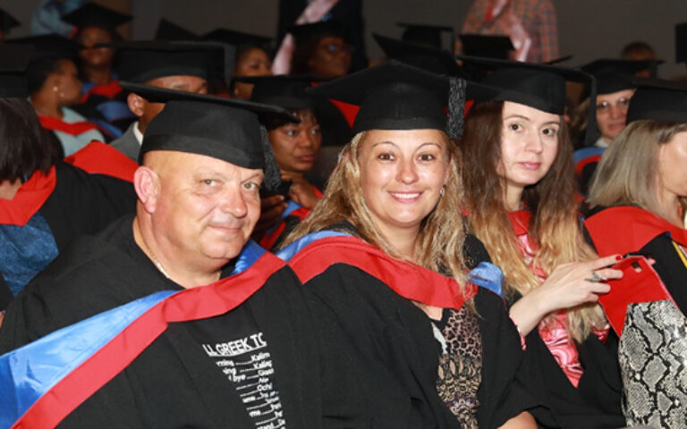 Graduates seated in caps and gowns smiling during ceremony, capturing memorable moments of a graduation ceremony
