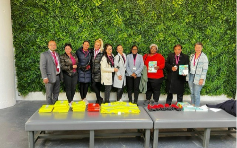 Group of volunteers standing by greenery wall with materials, celebrating community efforts during Great Big Green Week.