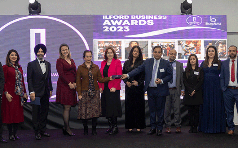 Group of professionals receiving award on stage at business event, celebrating success as Business of the Year.