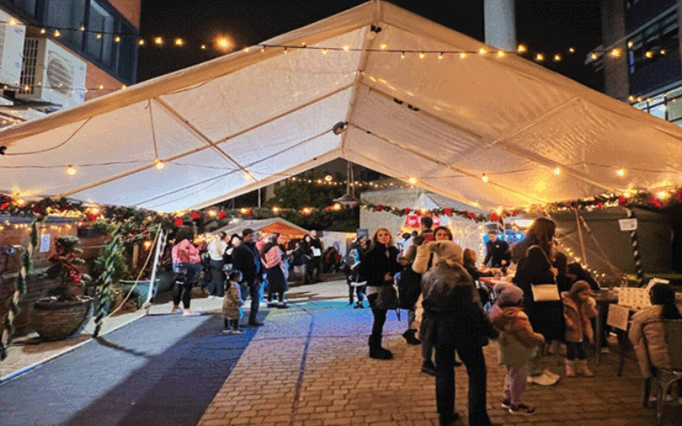 Outdoor Christmas fair under lit canopy with visitors, festive stalls, and decorations at Mont Rose College Hosts Enchanting Christmas Fair.