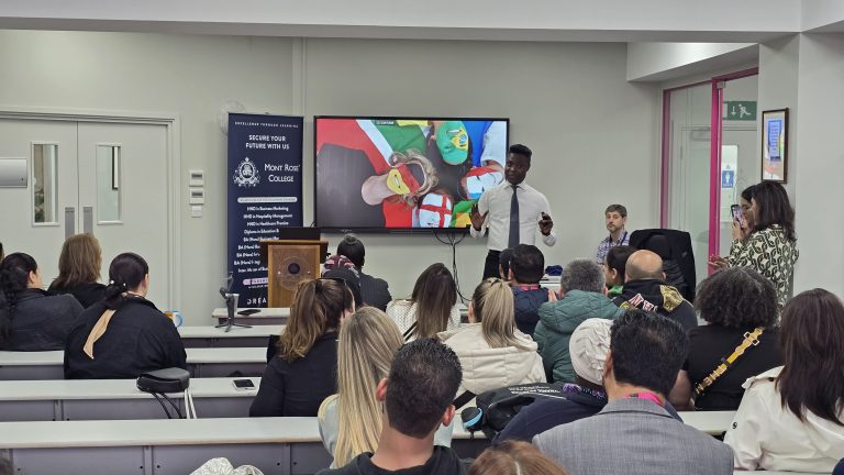 A speaker presents turning local business success into gold to an engaged audience at Mont Rose College