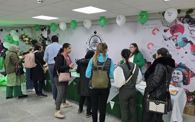 Attendees gather at Mont Rose College Macmillan Charity Event, decorated with green balloons and themed banners.