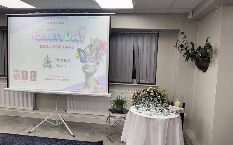 A projector screen and award table set up for Celebrating International Women&rsquo;s Day at Mont Rose College, honoring achievements and recognition.