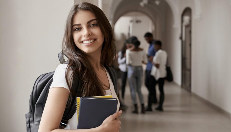 Smiling student holding notebooks in a hallway, symbolizing global career opportunities with an HND qualification.