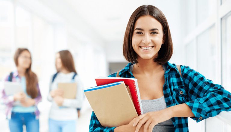 Smiling student holding notebooks in a hallway, symbolizing professional development through HND programs.