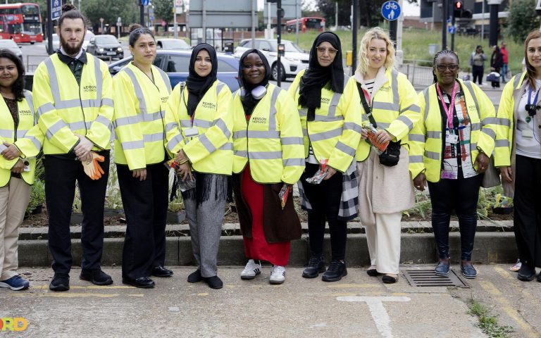 Group of volunteers in high-visibility jackets posing during Ilford Green Action Day community event.