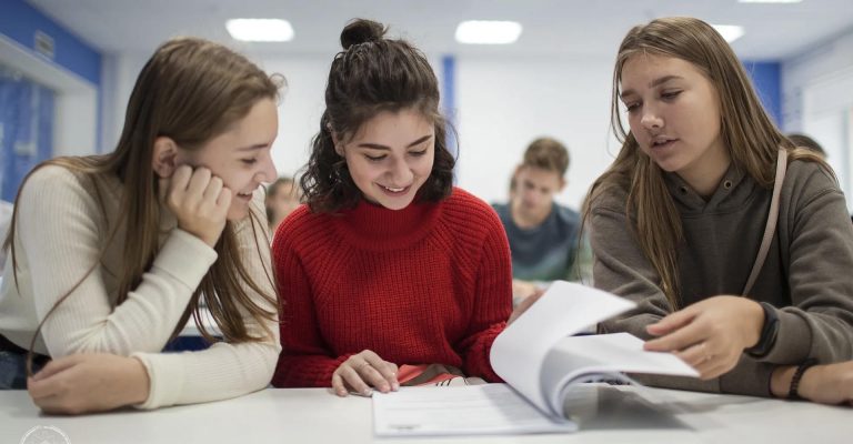 Three students discussing documents in class representing the topic HND vs professional qualifications in education