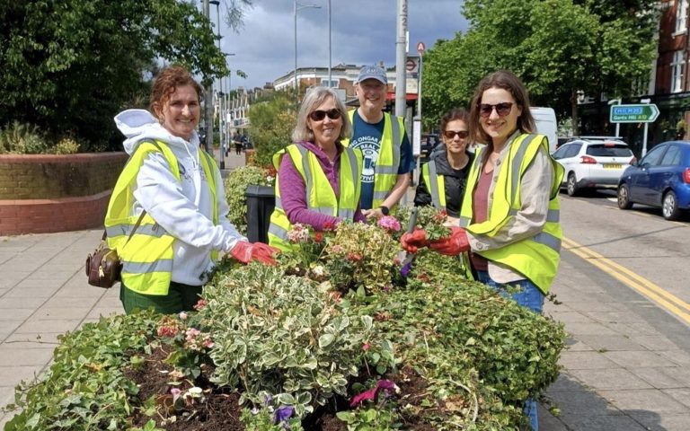 Volunteers planting flowers on a city street, supporting the Greener Redbridge community environmental initiative.