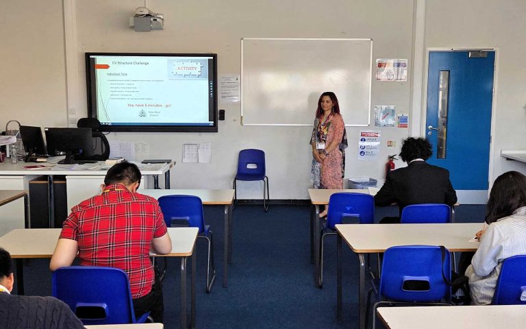 Classroom session with students writing as instructor leads the Empowering Future Talent: MRC Delivers CV & Cover Letter Workshop at Chadwell Heath Academy.