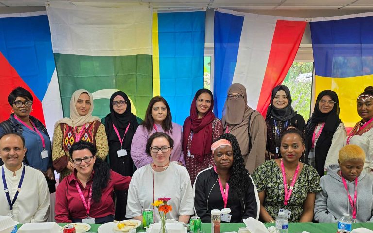 Group of staff and students posing with international flags in the background during Mont Rose College’s Multicultural Day.