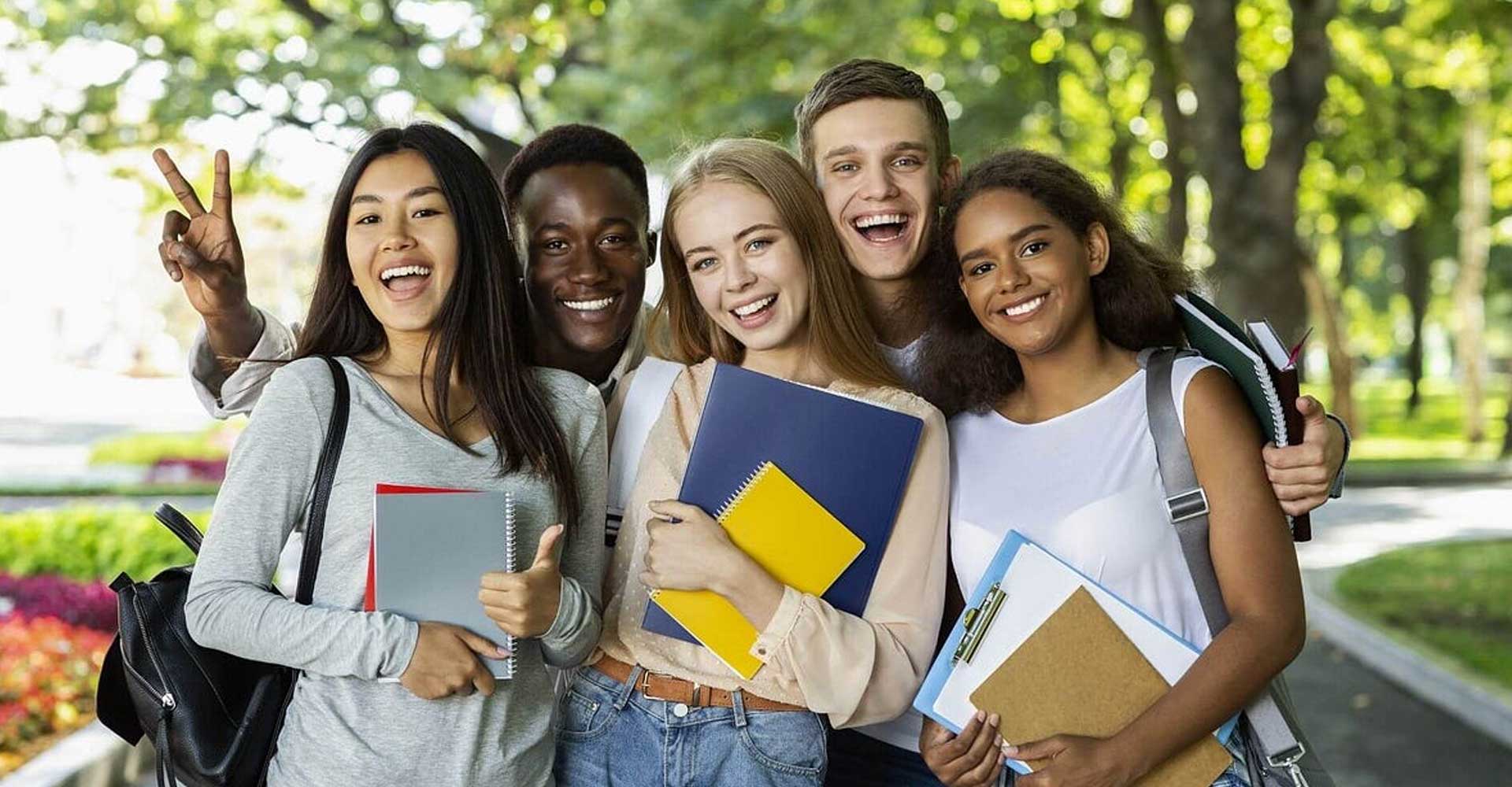Smiling students holding notebooks outdoors, representing academic qualifications needed for HND courses.