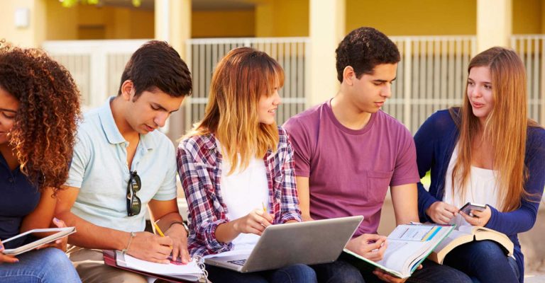 Group of diverse students sitting outdoors, studying together with books, laptop, and notes, representing collaborative learning and preparation for HND admissions.