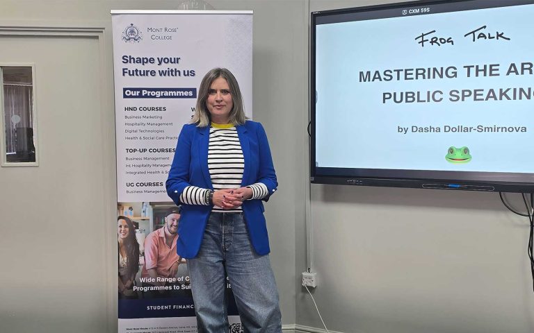Dasha Dollar-Smirnova standing beside screen at Mont Rose College Public Speaking Workshop presentation.