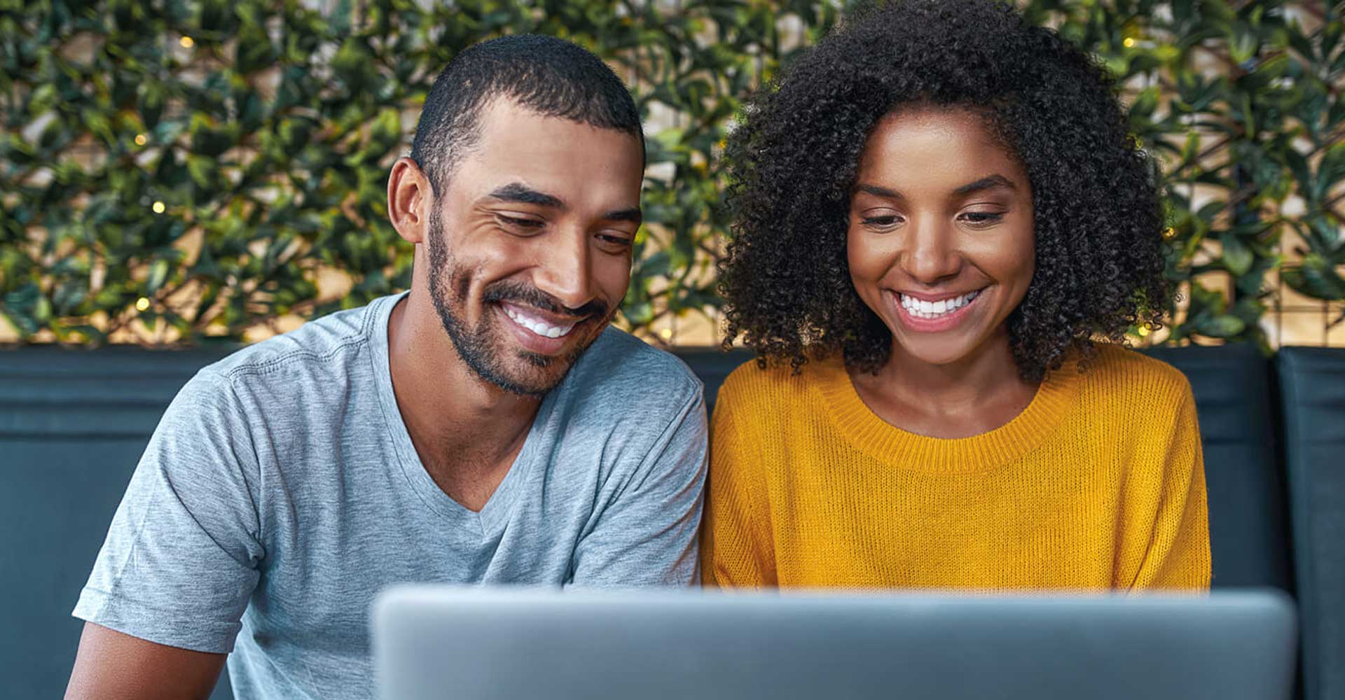 Smiling couple looking at laptop while researching How to Apply for an HND in London.