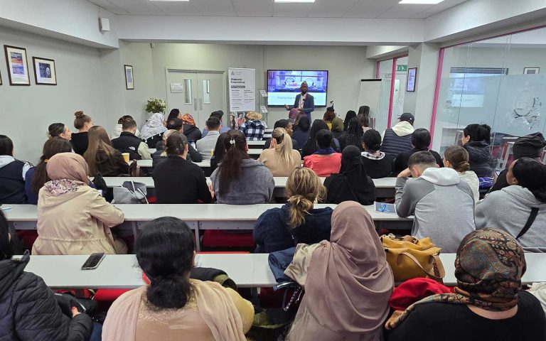 Students attending a Black History Month Antony Lindsay Mont Rose College lecture led by a speaker in a classroom.