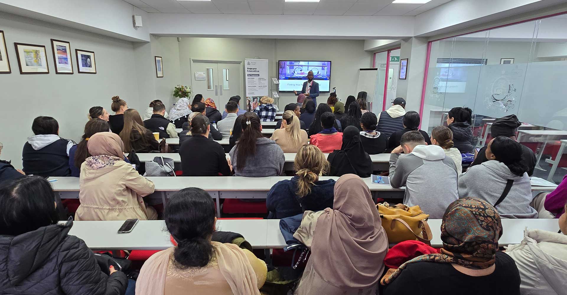 Students attending a Black History Month Antony Lindsay Mont Rose College lecture led by a speaker in a classroom.