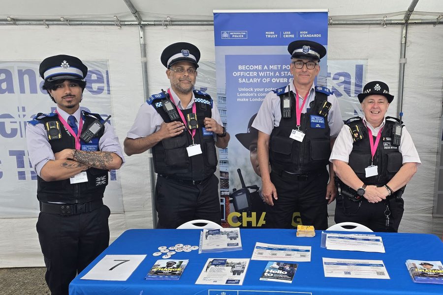 Police officers standing at recruitment booth with materials displayed, engaging visitors at Career Fair 2025