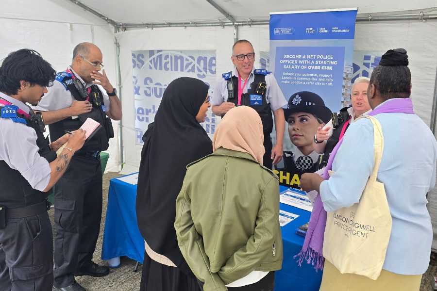 Visitors speaking with police representatives at information booth, learning about careers and opportunities at Career Fair 2025
