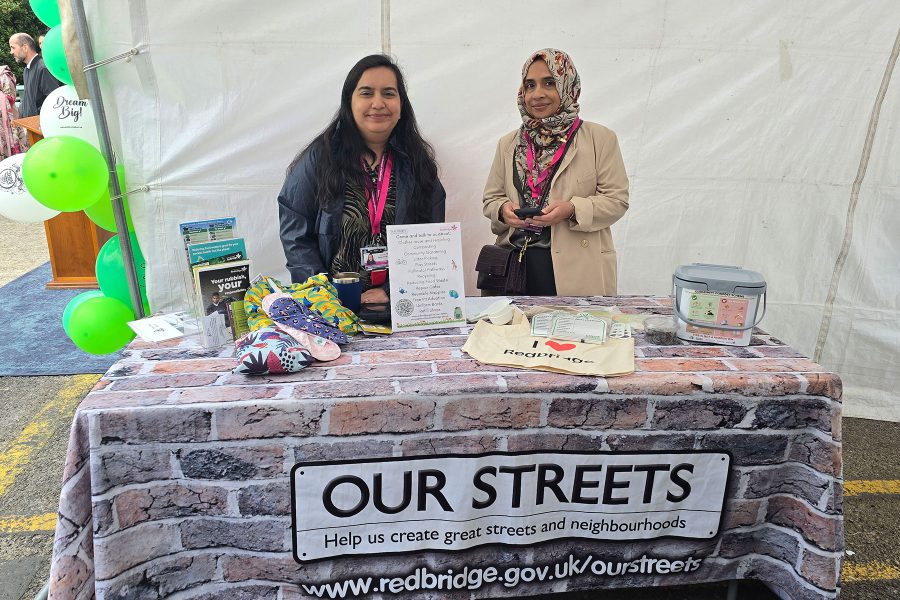 Two staff members at community information booth with resources displayed, engaging visitors at Career Fair 2025