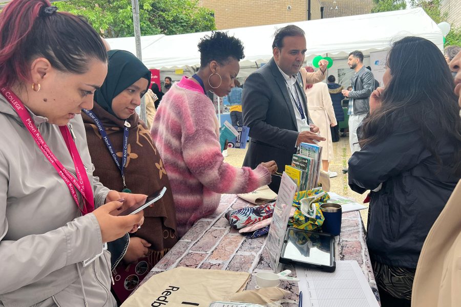 Visitors interacting with exhibitors at busy outdoor booth, exploring opportunities and networking during Career Fair 2025