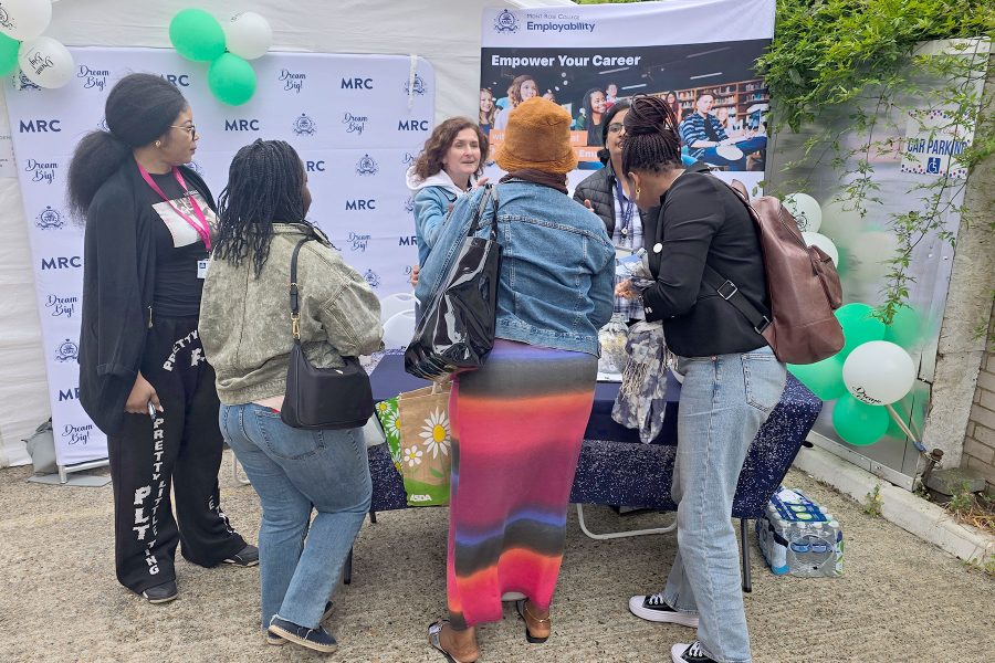 Group of visitors engaging with staff at Mont Rose College booth, networking and exploring opportunities at Career Fair 2025