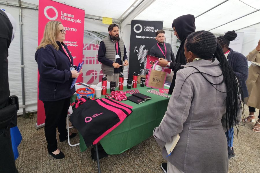 Visitors interacting with Lanes Group exhibitors at promotional booth, exploring careers and networking at Career Fair 2025