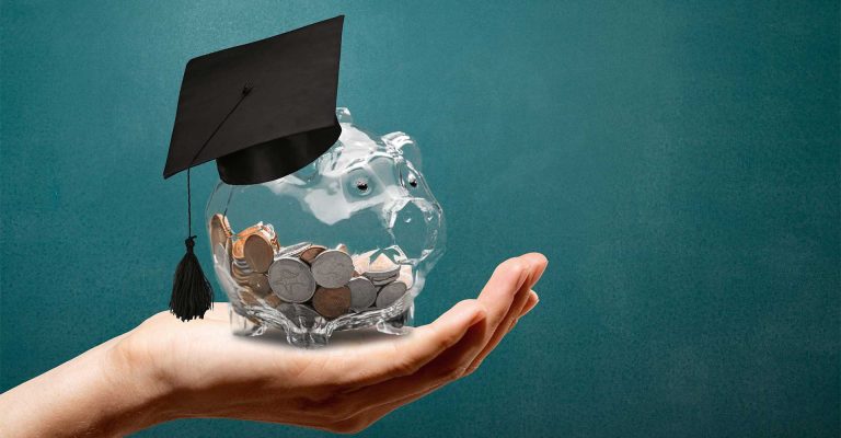 Hand holding piggy bank filled with coins and graduation cap, symbolizing Funding Your HND and student financial support