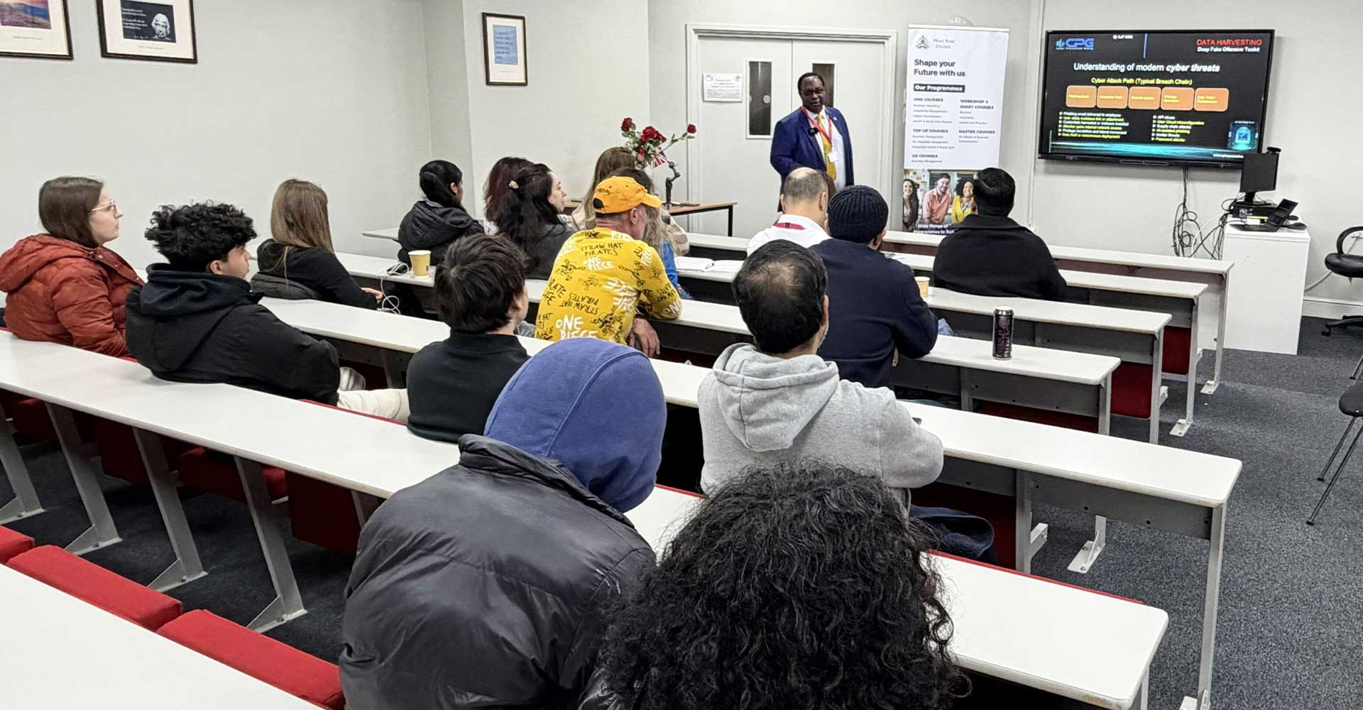 Audience attending a classroom session on cybersecurity threats and protection strategies at Mont Rose College while the speaker presents key cyber risk concepts.