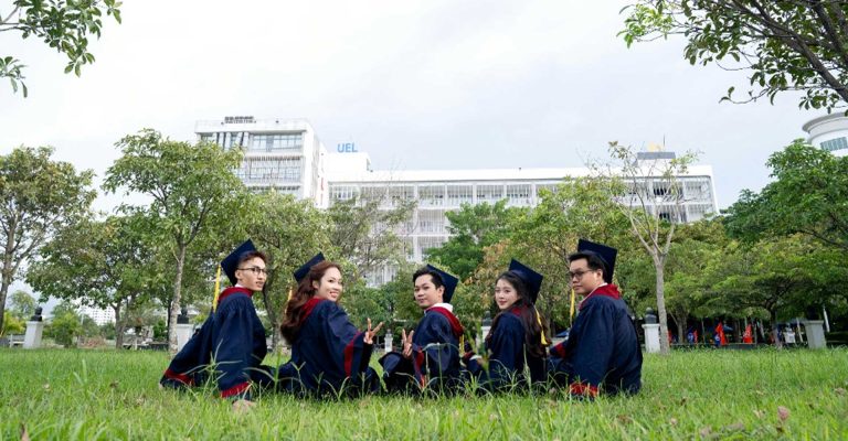 Graduates in caps and gowns sitting on campus grounds, comparing educational pathways in HND vs university degree options.