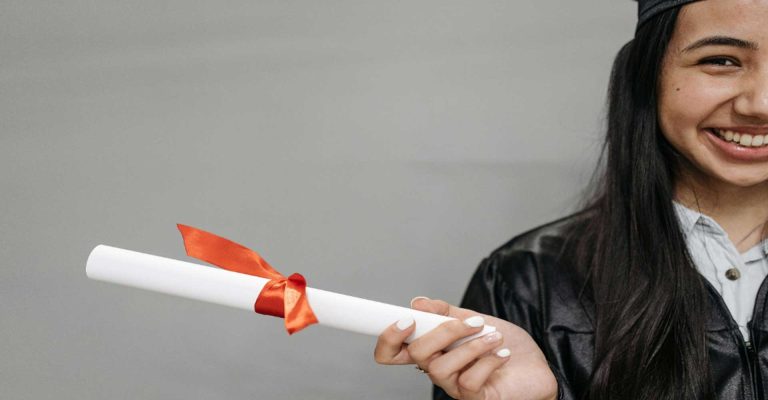 Smiling graduate holding a diploma scroll, celebrating academic success and achievement through an HND Qualification.