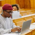 Student working on a laptop in a lecture hall, developing academic skills through Level 5 courses UK programmes.