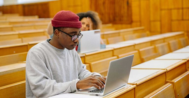 Student working on a laptop in a lecture hall, developing academic skills through Level 5 courses UK programmes.